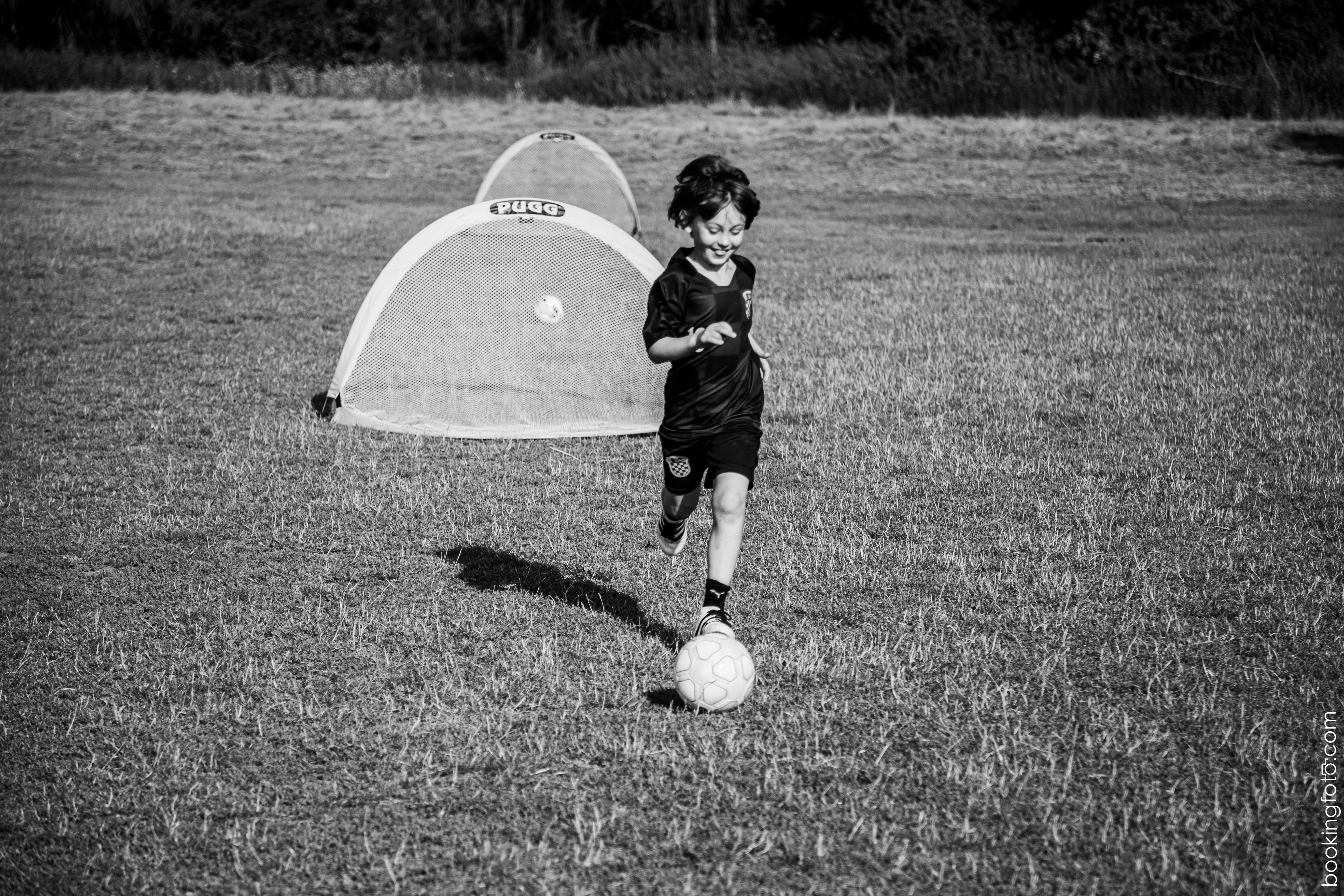 Kind mit strahlendem Lächeln dribbelt auf Mini-Tor zu – FUNino-Training